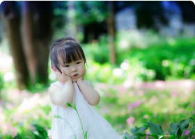 Child sitting thoughtfully in a garden